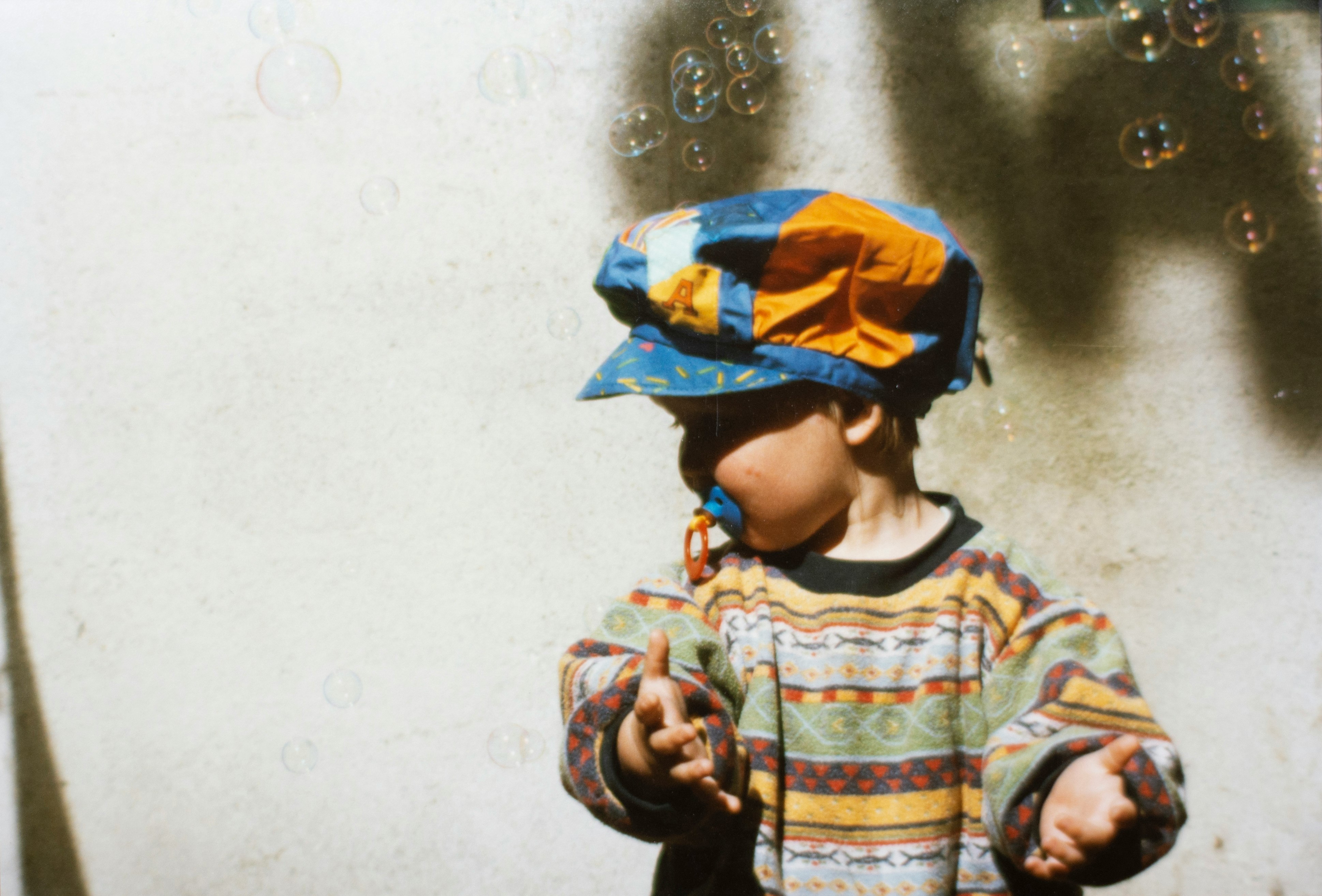 child in multicolored top sucking a pacifier